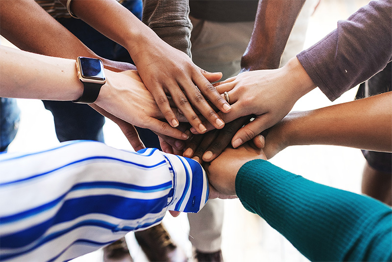 Group of diverse hands stacked together in a teamwork gesture