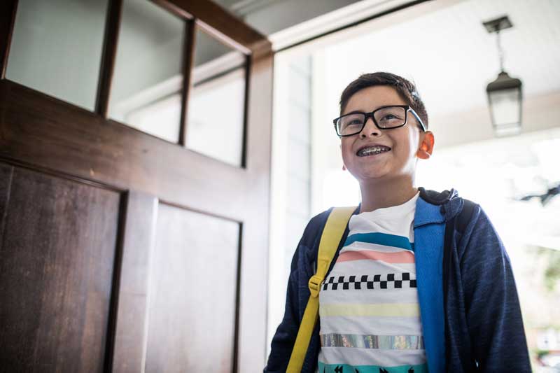 Young boy wearing a backpack entering a home.